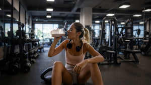 Person drinking a protein shake after a workout in a gym.